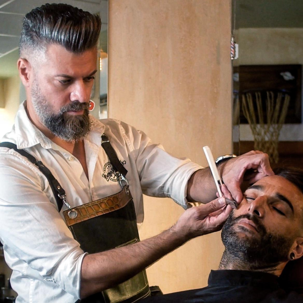 Barbero realizando un corte de cabello en una barbería / Barber providing a haircut in a professional barbershop
